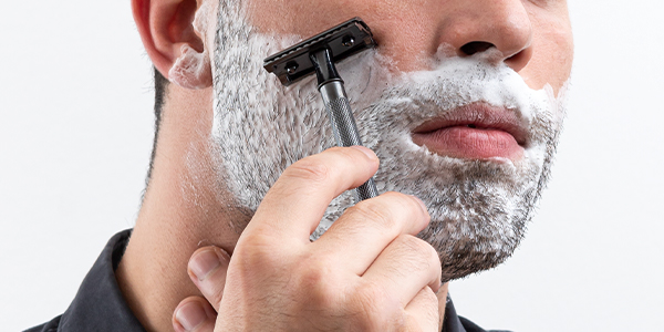 Mann mit eingeschäumten Bart rasiert sich mit schwarzem Rasierhobel der Marke Merkur